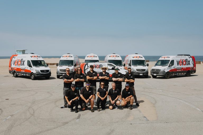 Los Angeles Velofix team posing in front of 7 velofix vans